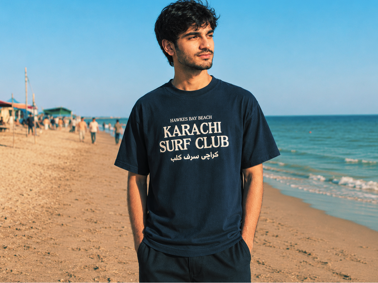 Man wearing a 'Karachi Surf Club' t-shirt on a beach